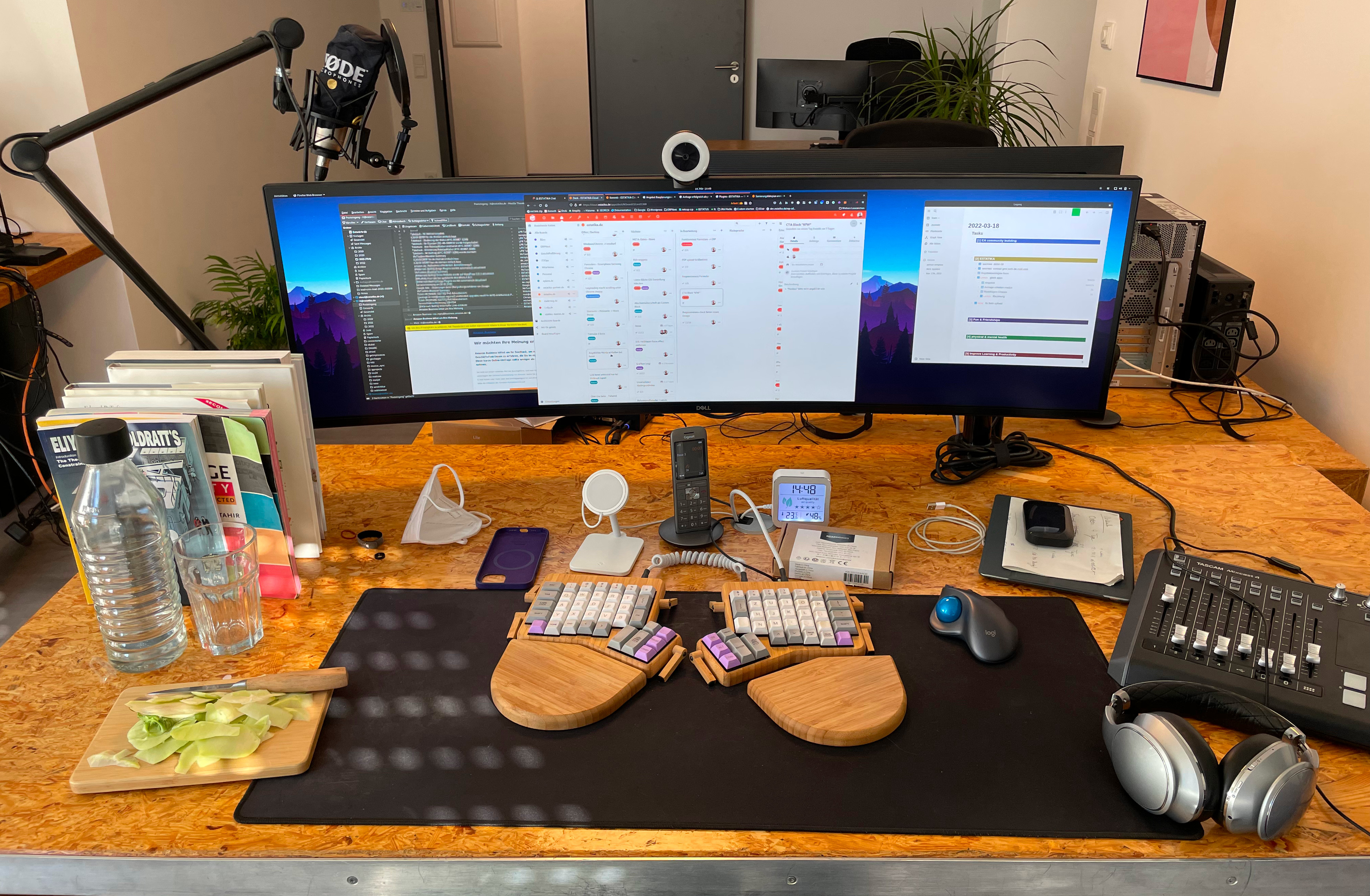 A desk with a widescreen monitor and an ergodox keyboard.